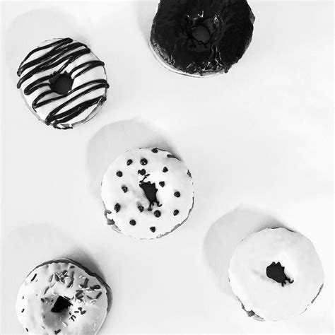 Four Donuts With White Frosting And Chocolate Sprinkles Arranged In A