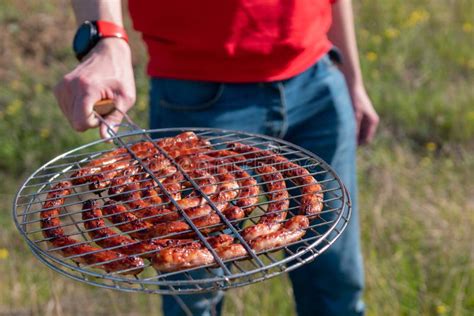 Man Holding Grilling Basket With Roasted Sausages Grilling Sausages On Barbecue Grill Bbq