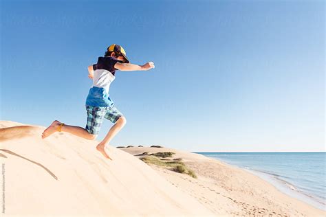 Boy Leaping Off Large Sand Dunes At The Ningaloo Coast By Stocksy