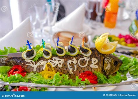 Whole Stuffed Fish On An Oblong Dish Decorated With Lemon Vegetables