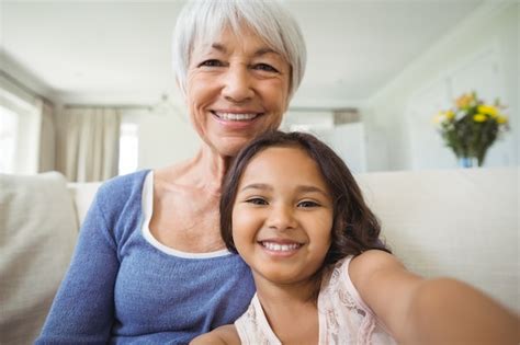 Premium Photo Portrait Of Smiling Granddaughter And Grandmother Sitting On Sofa In Living Room