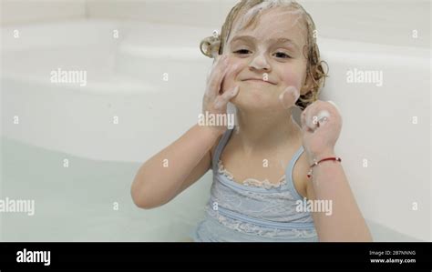 Attractive Four Years Old Girl Takes A Bath With Bath Foam In Swimwear Washes Her Head Wet