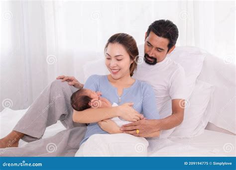 Beautiful Wife Leaning Her Back To Husband Leg While Hold Newborn With