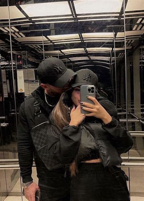 A Man And Woman Standing In Front Of A Mirror Taking A Selfie With