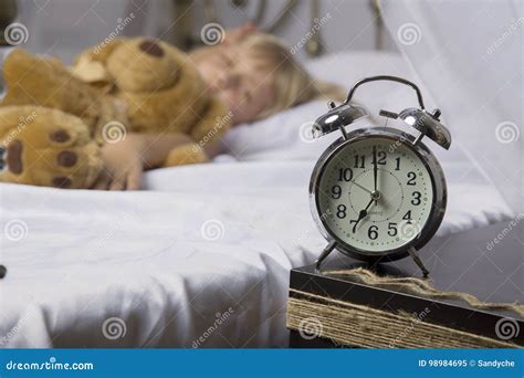 Alarm Clock Standing On Bedside Table Wake Up Of An Asleep Young Girl