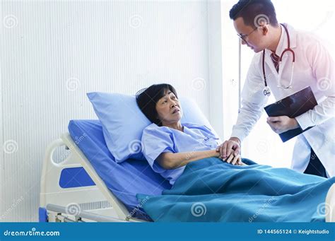 Man Doctor Checking Pressure Of Female Patient Older Sick Woman Patient Lay On Bed In Hospital