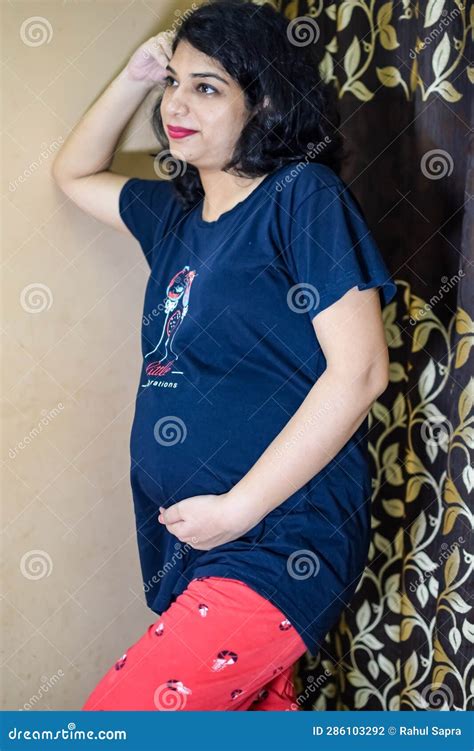 a pregnant indian lady poses for indoor pregnancy shoot and hands on belly indian pregnant