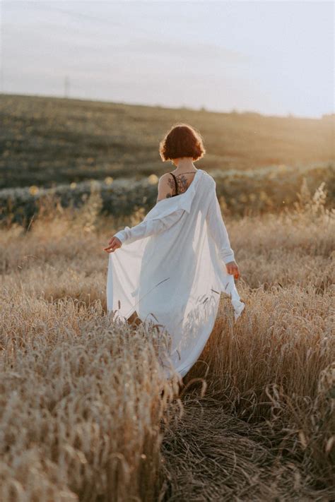 Woman In White Dress Walking On Brown Grass Field During Daytime Photo