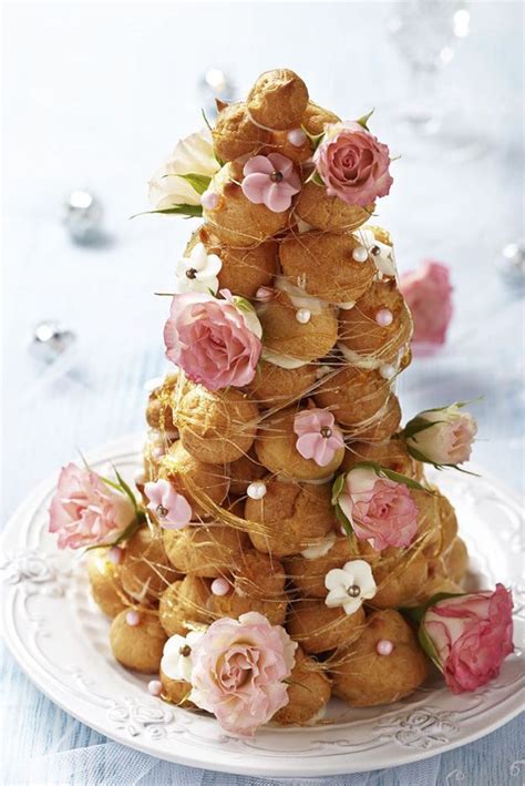 A Tower Of Pastries Decorated With Flowers On A White Plate And Blue Tablecloth