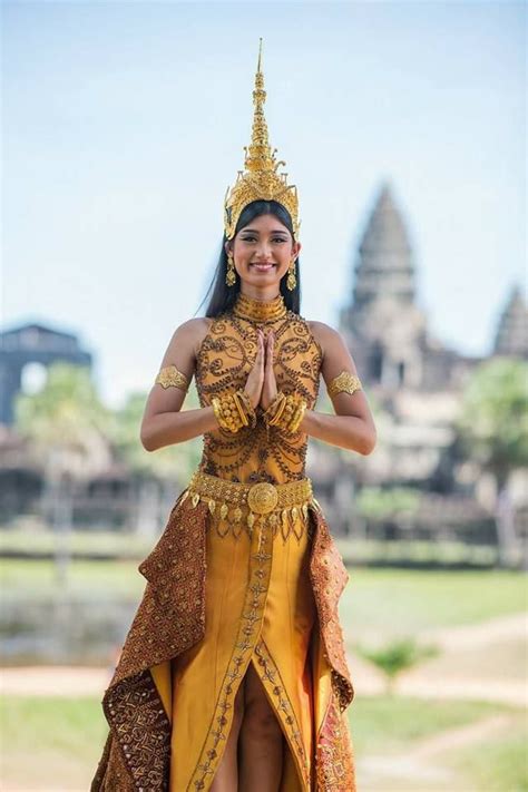 A Woman Dressed In An Elaborately Designed Costume Poses For The Camera With Her Hands Clasped