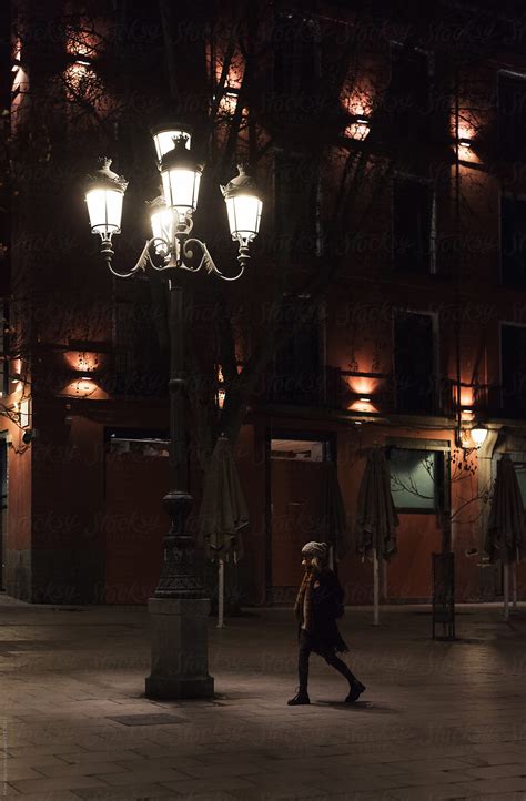 Anonymous Woman Walking On Illuminated Winter Street By Stocksy