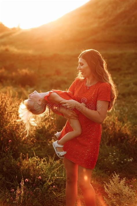 Portrait Of A Mother Holds Throws Up And Spins The Daughter On Hands