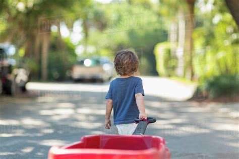 Caucasian Boy Pulling Red Wagon In Street Stock Photo Dissolve