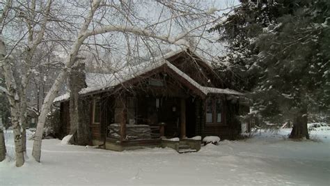 Log Cabin Sitting In Trees Pan Out To Snow Covered Field