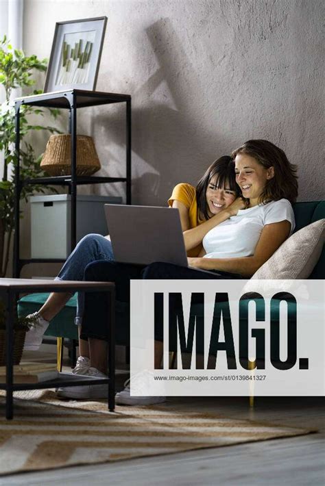 Happy Lesbian Couple Using Laptop While Sitting At Home Model Released Symbolfoto Property Released