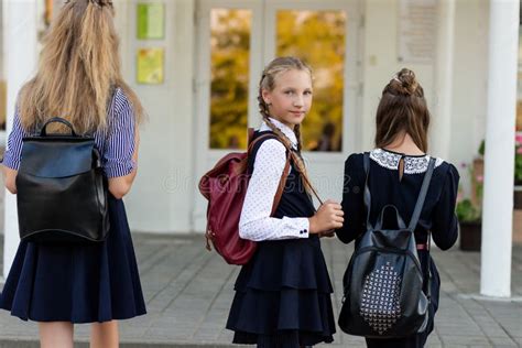 Drei Mädchen In Der Schuluniform Mit Rucksäcken Stehen Auf Den