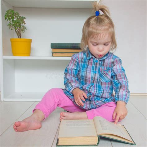 Ein Kleines Mädchen Sitzt Auf Dem Boden Und Liest Ein Buch Der Ch Stockbild Bild Von