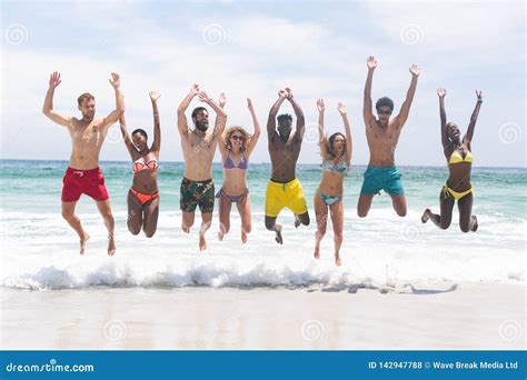 Group Of Friends Relaxing And Jumping In Water At Beach Stock Photo Image Of Calm Environment