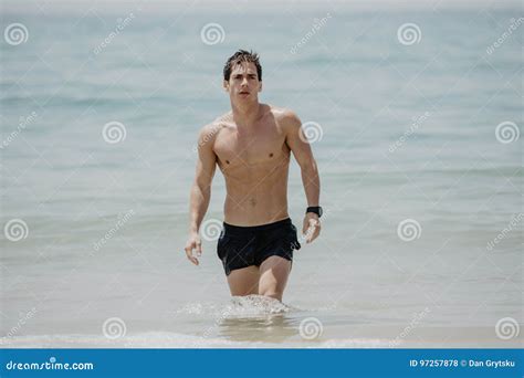 Young Handsome Muscular Man Walking Out Of The Water In A Tropical