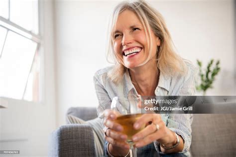 Smiling Caucasian Woman Sitting On Sofa Drinking White Wine High Res