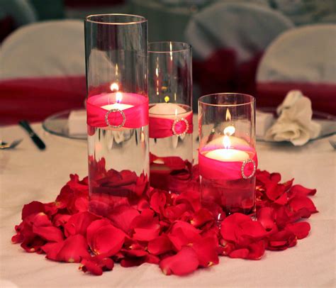 3 Glass Cylinder Wedding Centerpiece With Floating Candles And Pink Ribbon Surrounded By Pink