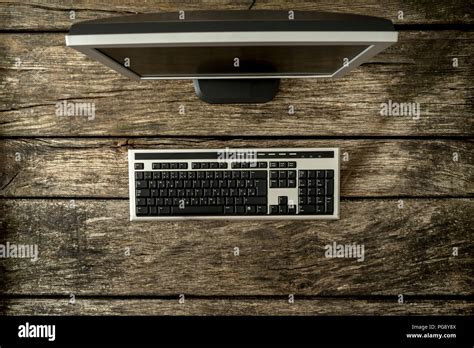 Top view of office computer keyboard and monitor on a textured wooden