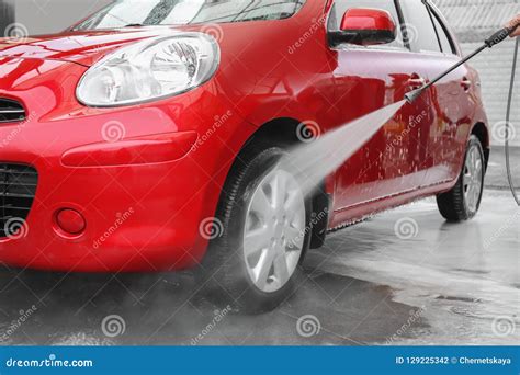 Male Worker Cleaning Vehicle With High Pressure Water Stock Photo