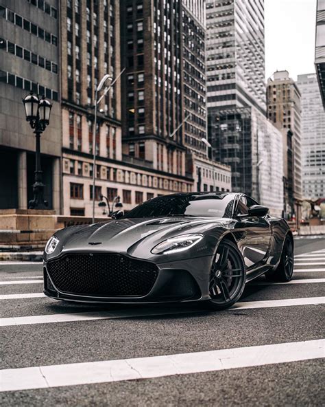 A Black Sports Car Parked On The Side Of A Road In Front Of Tall Buildings