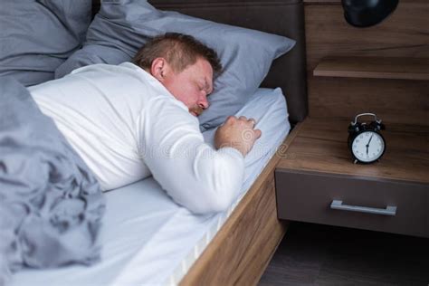 An Adult Man Wakes Up To The Alarm Clock On The Bed Stock Photo Image