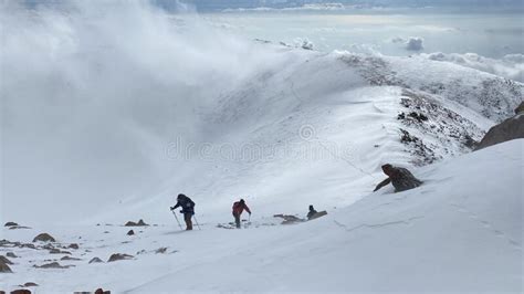 Climbers With Small Backpacks And Trekking Poles Are Walking On A Snowy