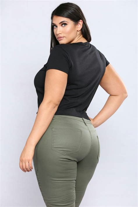 A Woman In High Waisted Green Pants And Black Top Is Posing With Her