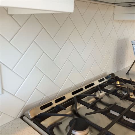 3x6 White Subway Tile In A Herringbone Pattern With Light Gray Grout