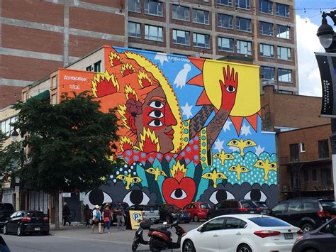 A Large Mural On The Side Of A Building In An Urban Area With Parked