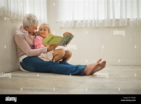 Smiling Grandmother Reading A Story With Her Granddaughter Stock Photo