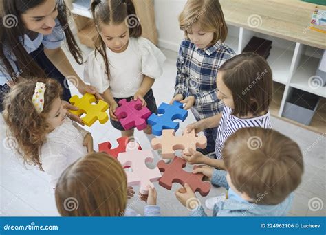 Team Of Little Children Together With Their Teacher Join Pieces Of A