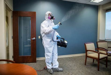 Workers Spray Disinfectant In Offices To Help Control The Spread Of The