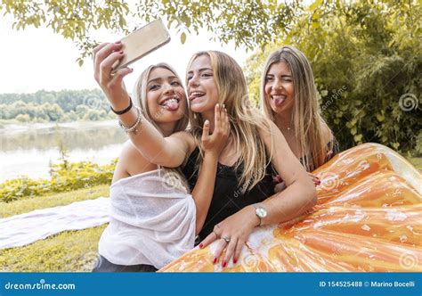 Female Millennial Girlfriends Taking A Selfie Outdoors On The River