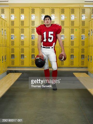 Teenage Boy Dressed For Football Standing In Locker Room High-Res Stock