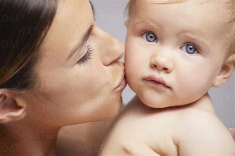Mother Kissing Baby On Cheek Stock Photo