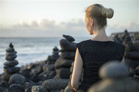 Spain Tenerife Costa Adeje Woman Sitting Between Cairns At The Coast