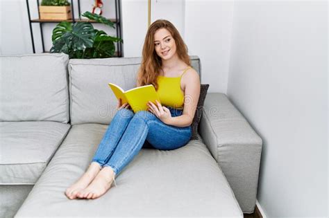 Young Redhead Girl Smiling Happy Reading Book At Home Stock Image