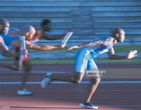 Athlete Passing The Baton In A Relay Race High Res Stock