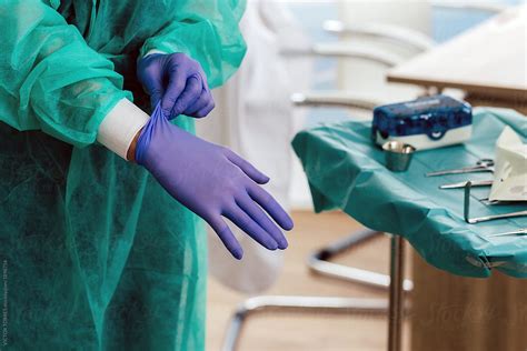 Surgeon Putting On Gloves Before Operation By Victor Torres