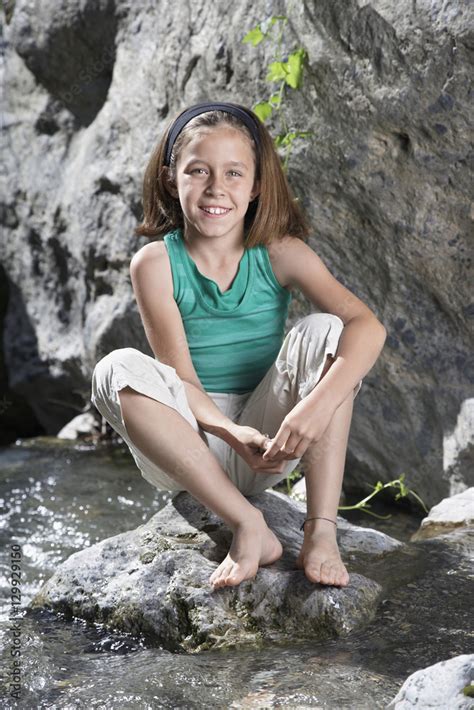 Full Length Portrait Of A Smiling Babe Girl Sitting On Rock By Stream Stock Foto Adobe Stock