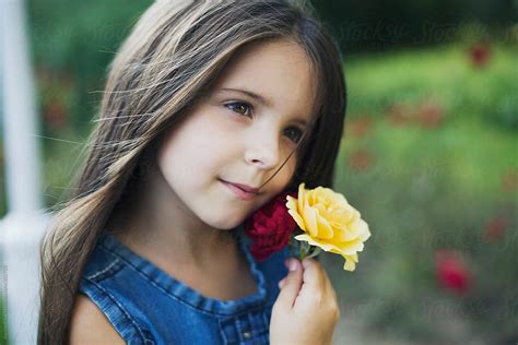 Little Girl Holding Rose Flower To Her Face By Stocksy Contributor