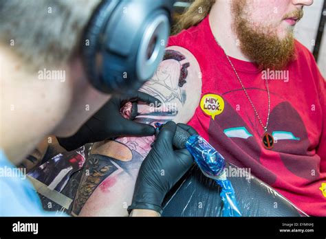 Tattoo Studio Tattoo Artist At Work Tattooing With A Machine Needle