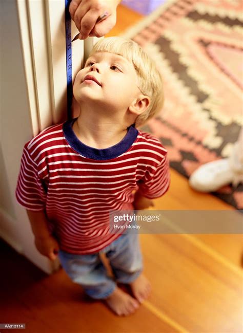 Mother Measuring Height Of Her Son In Door Frame High Res Stock Photo