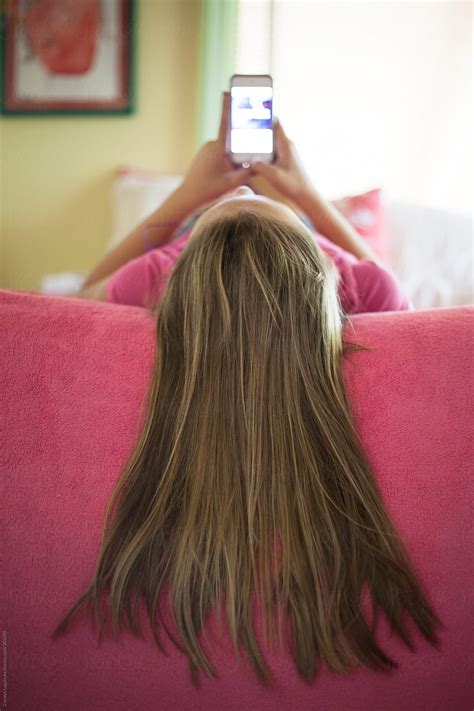 Young Girl Laying On Her Bed Texting Long Hair Over The Side Of The Bed By Carolyn Lagattuta