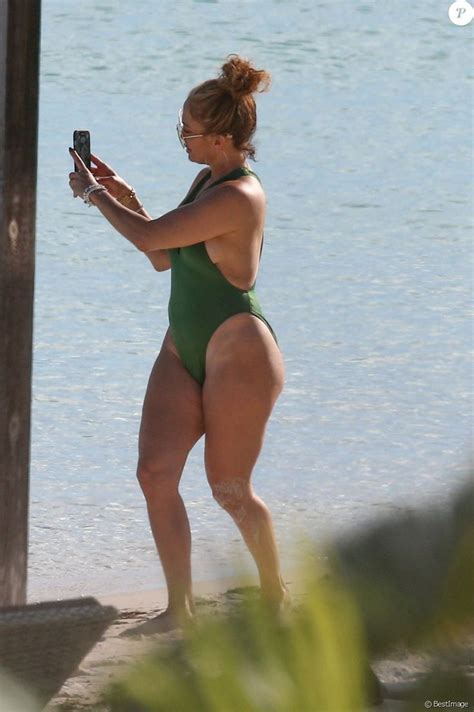A Woman In A Green Bathing Suit Taking A Selfie On The Beach With Her Cell Phone