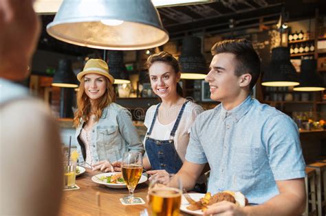 Happy Friends Eating And Drinking At Bar Or Pub Stock Photo Image Of